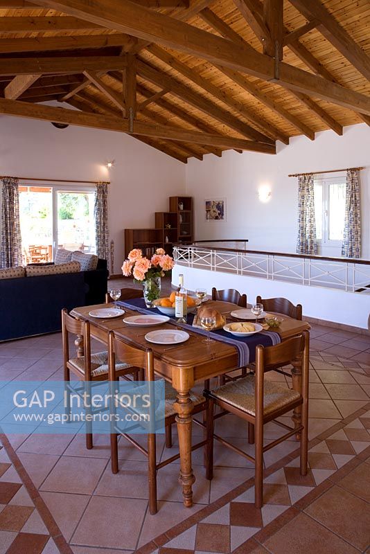 Villa Christina, Kaminaki, Corfu, Greece. Open plan living and dining room with table and stone tiled floor