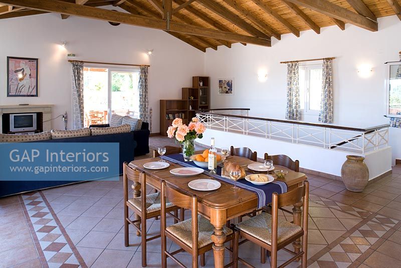 Villa Christina, Kaminaki, Corfu, Greece. Open plan living and dining room with table and stone tiled floor