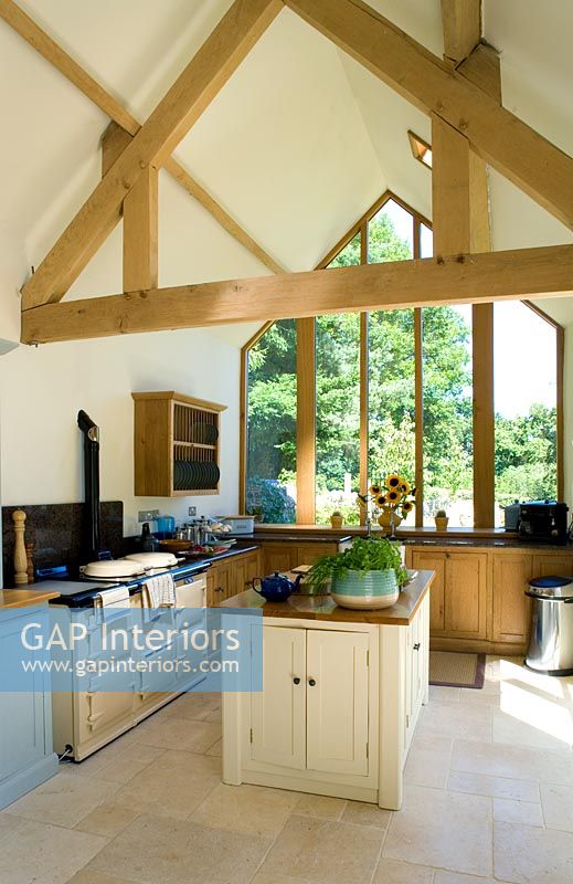 Kitchen with island, exposed roof beams, limestone floor and aga. 