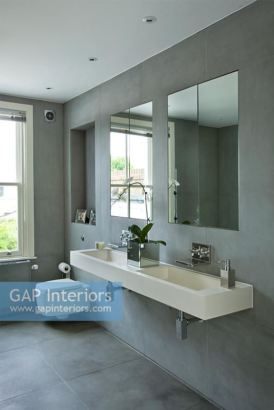 Modern bathroom with wall mounted double stone sink in grey slate tiled bathroom  twin with mirrors