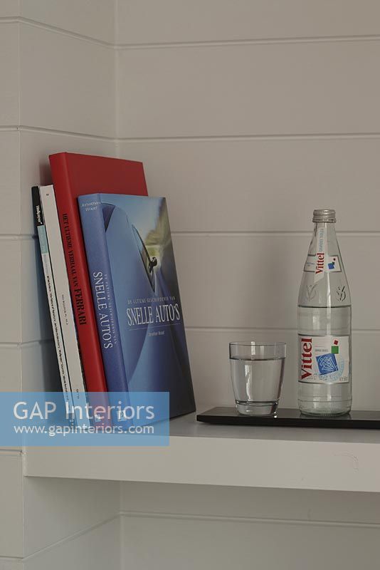 Books and water bottle with glass on shelf