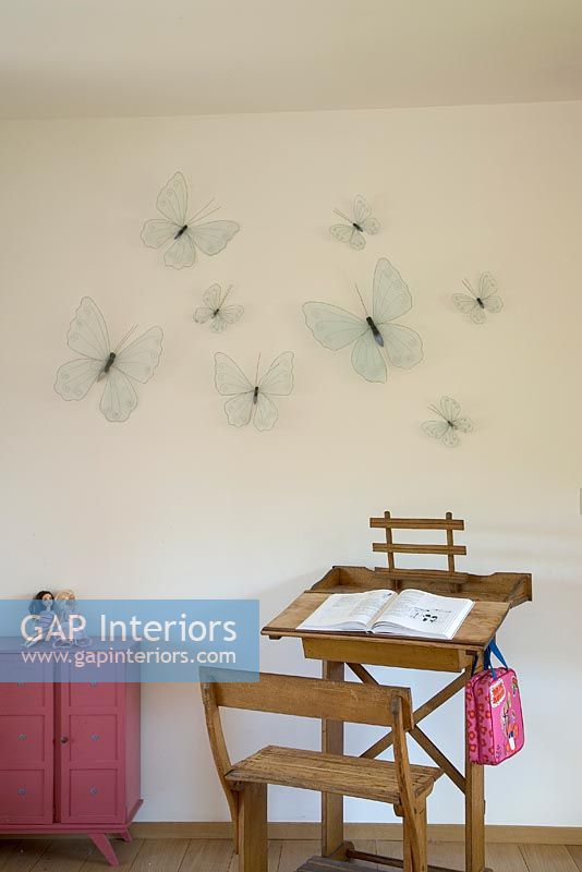 Wooden desk and chair with butterflies on wall