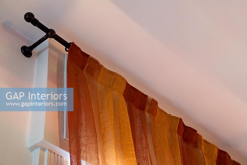Close up of orange curtains and iron curtain rail