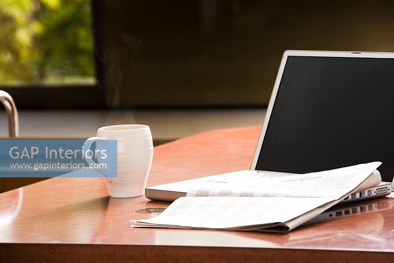 Laptop, Coffee Mug, and Newspaper on Kitchen Counter