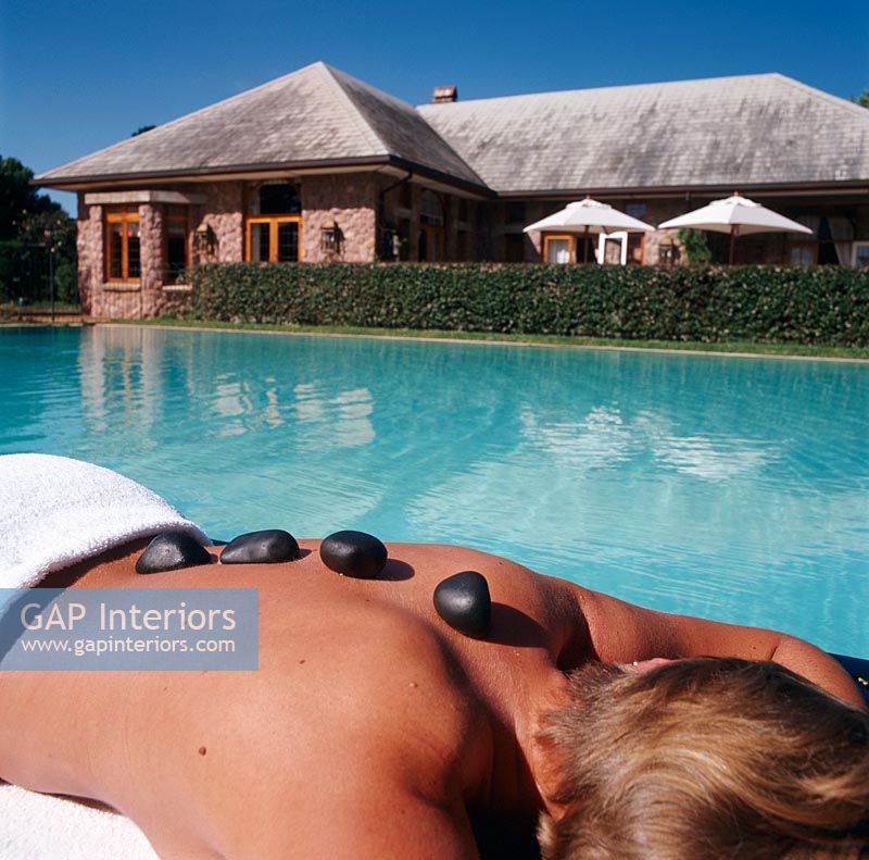 Woman receiving hot stone therapy by pool