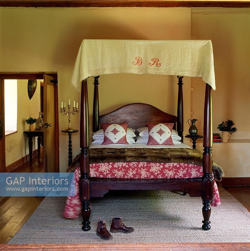 Four poster bed in bedroom with footwear