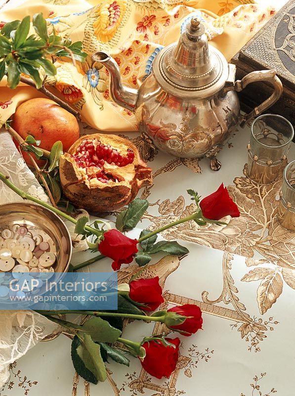 Overhead view of silver teapot and a bouquet of roses