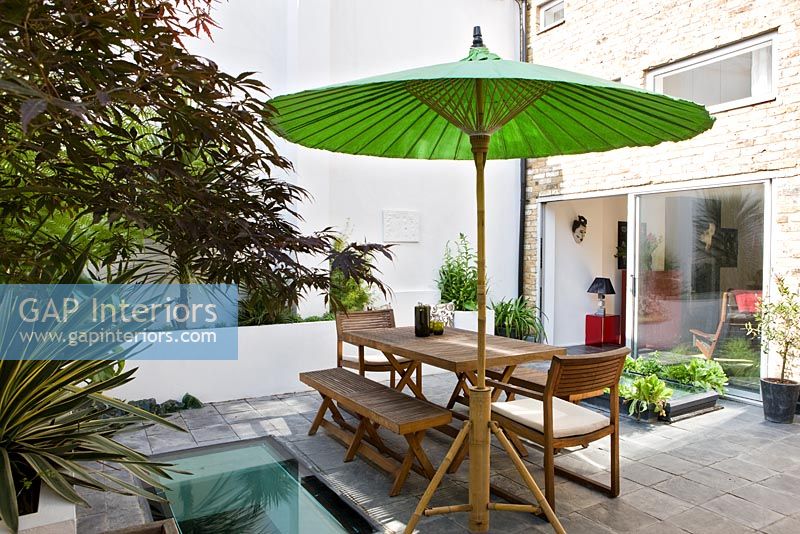 Small urban garden with wooden furniture and green parasol