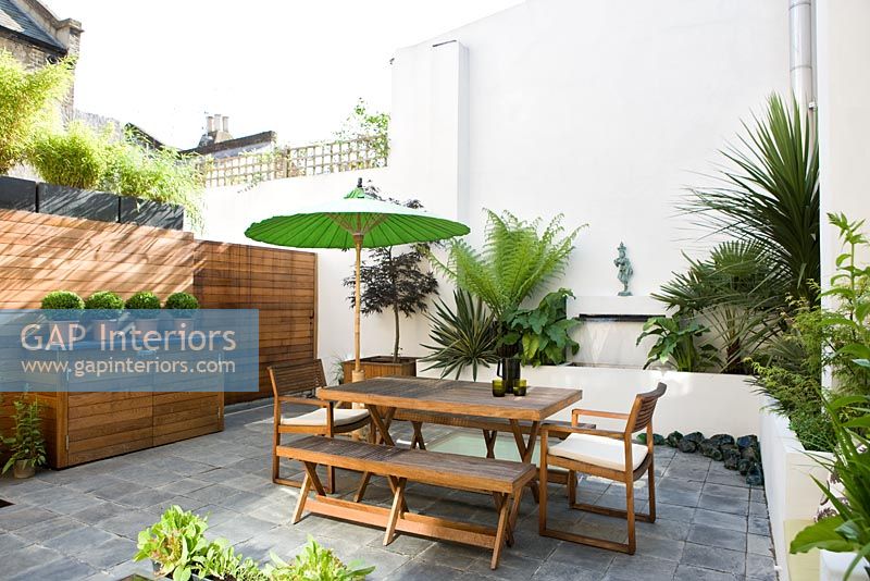 Contemporary patio garden with wooden furniture and green parasol