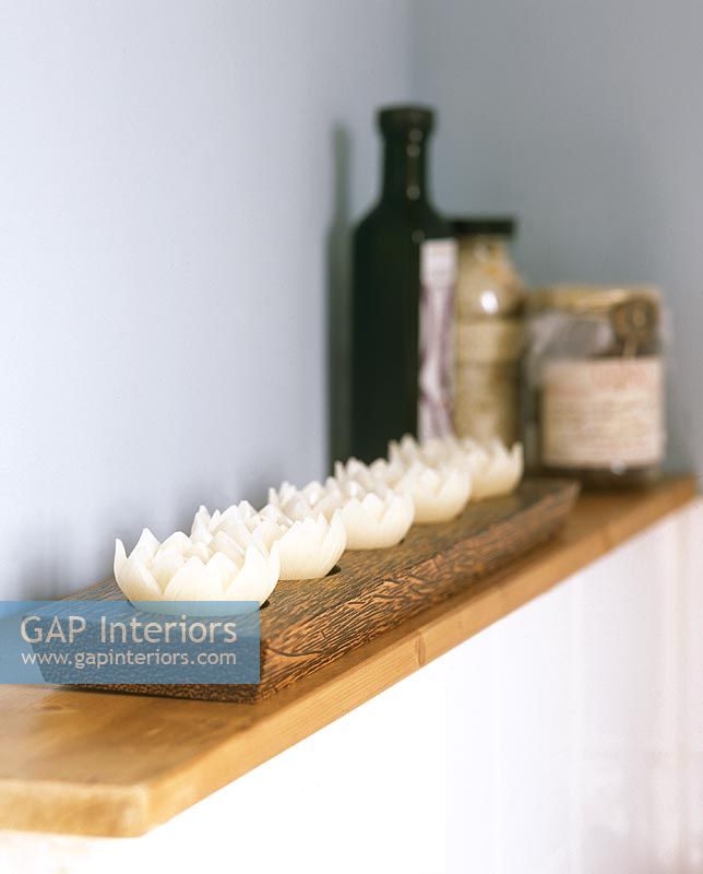 Row of lotus shaped candles on wooden tray