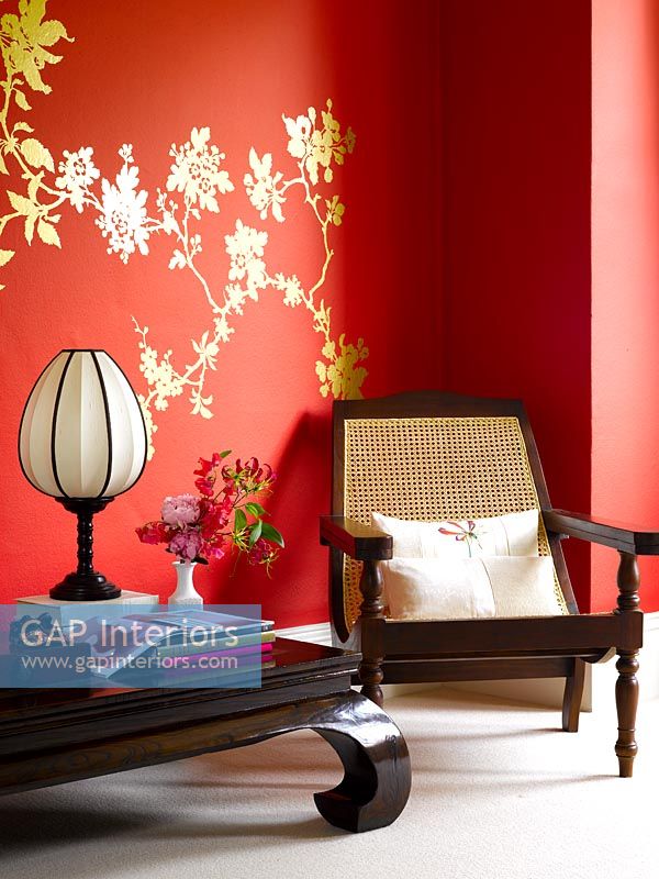 Dark wood oriental style furniture against red wall