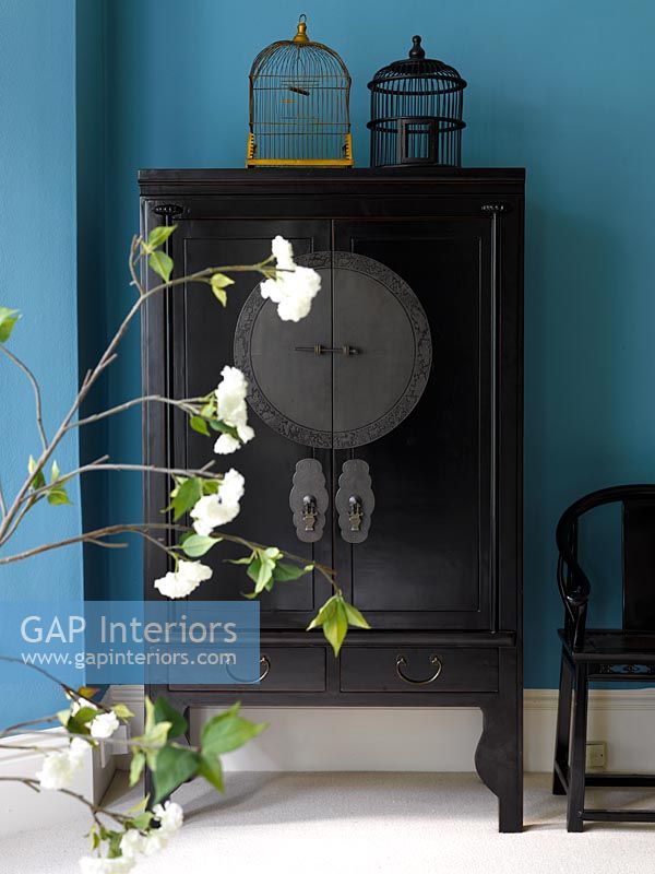 Dark wood oriental style cabinet against blue wall