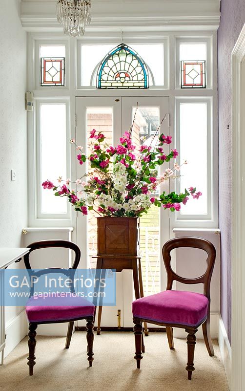 Flower stand and chairs by stained glass window