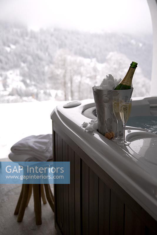 Ice bucket with champagne on edge of hot tub 