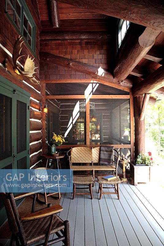 Garden furniture on porch of log cabin 