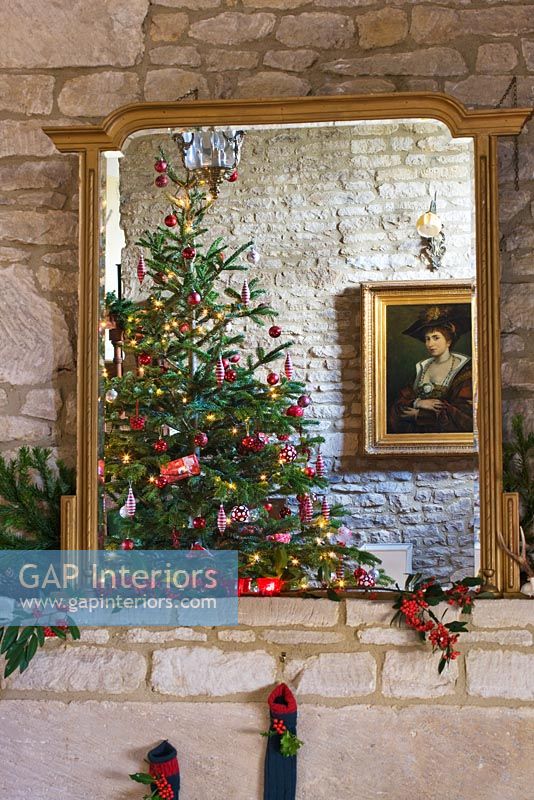 Gilt mirror above cotswold stone fireplace at Christmas