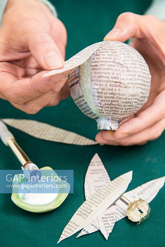Create a simple Christmas bauble using newspaper -  attaching strips of paper to bauble