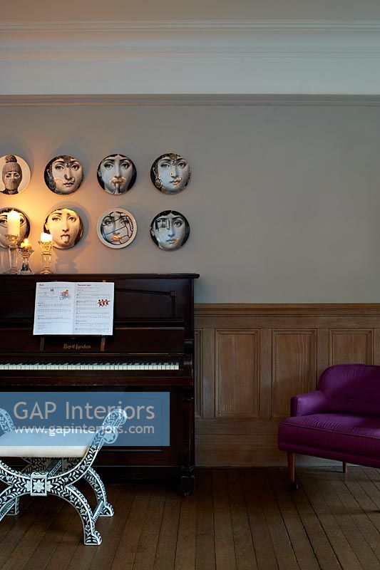 Patterned plates hung above piano