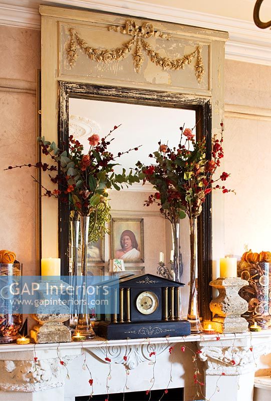 Ornate mantlepiece with french mirror, stone candlesticks and christmas floral displays