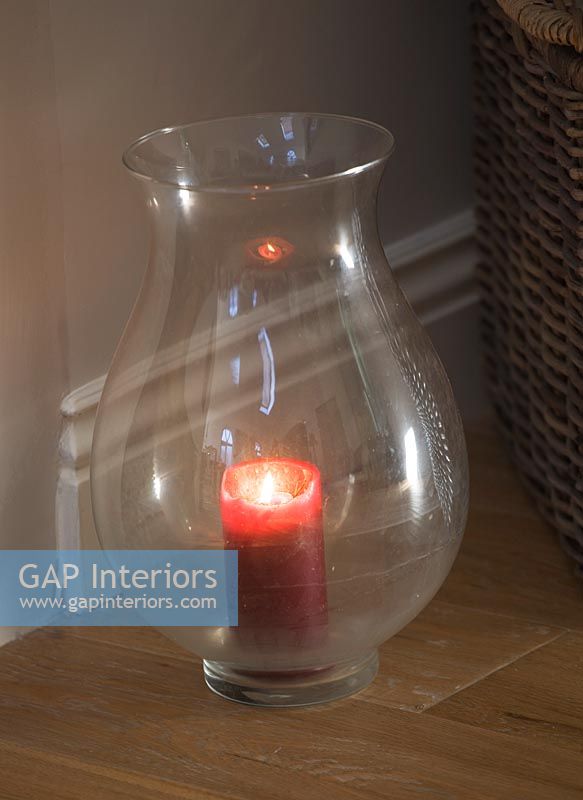 Glass storm lantern with red candle