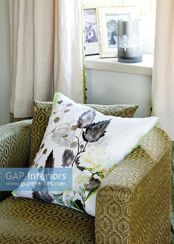 Patterned cushion on green armchair