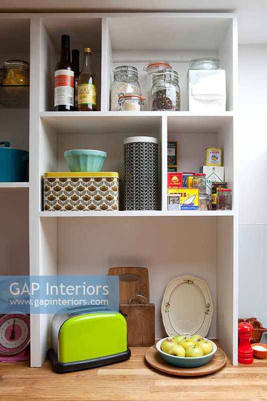 Colourful tins and crockery on kitchen shelves