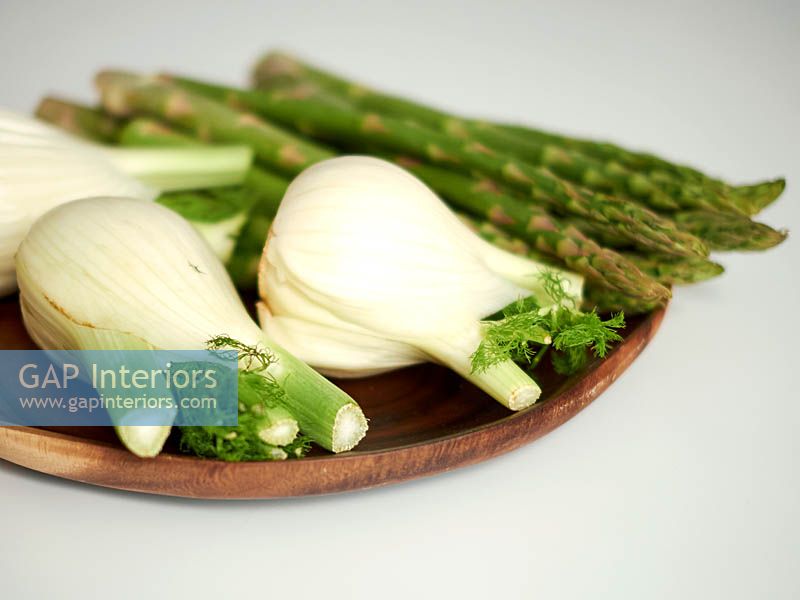 Fennel bulbs and asparagus spears in wooden bowl