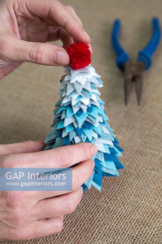 Making a felt christmas tree - Add the pom pom to the top of the tree to finish it off