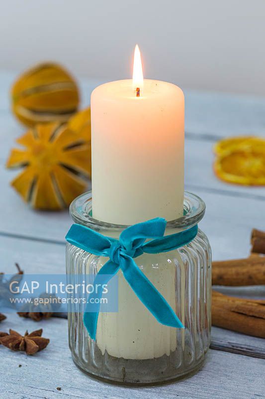 Candle in a glass jar with a felt ribbon, accompanied with Christmas themed items 