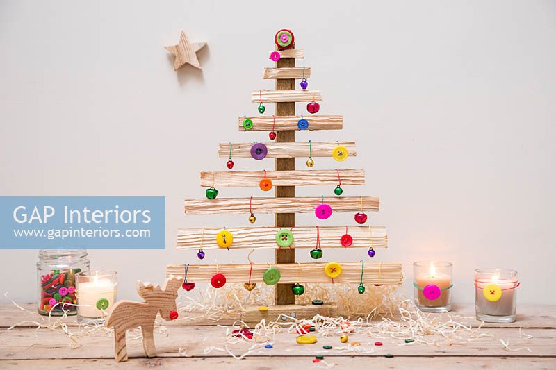 A wooden Christmas tree decorated with coloured buttons and baubles 
