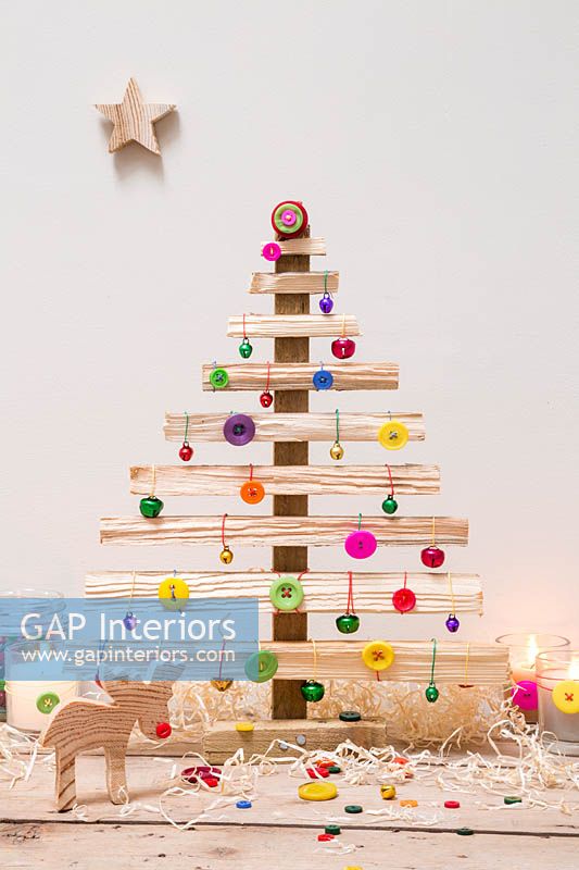 A wooden Christmas tree decorated with coloured buttons and baubles 