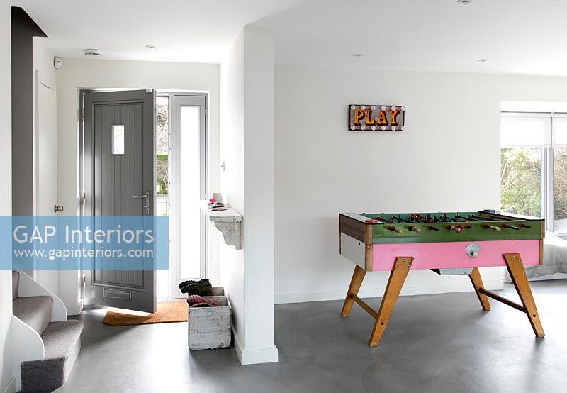 Entrance to open plan house with games table and concrete flooring