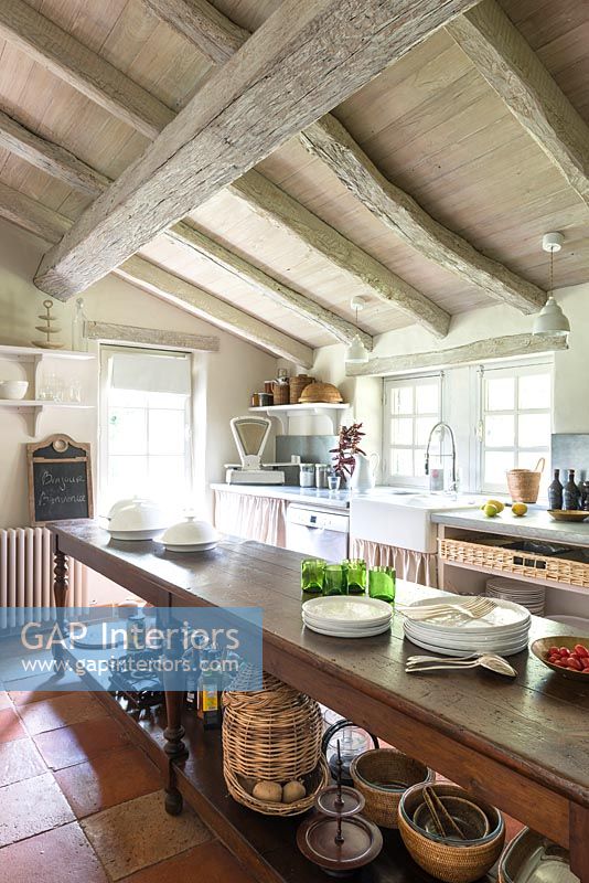 Long wooden island in country kitchen with exposed beams 