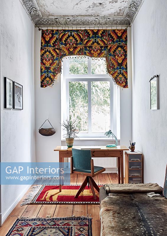Eclectic study with colourful decorative fabric over window 