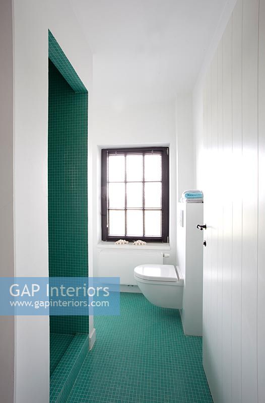 Modern bathroom tiled throughout in aqua green mosaic tiles 