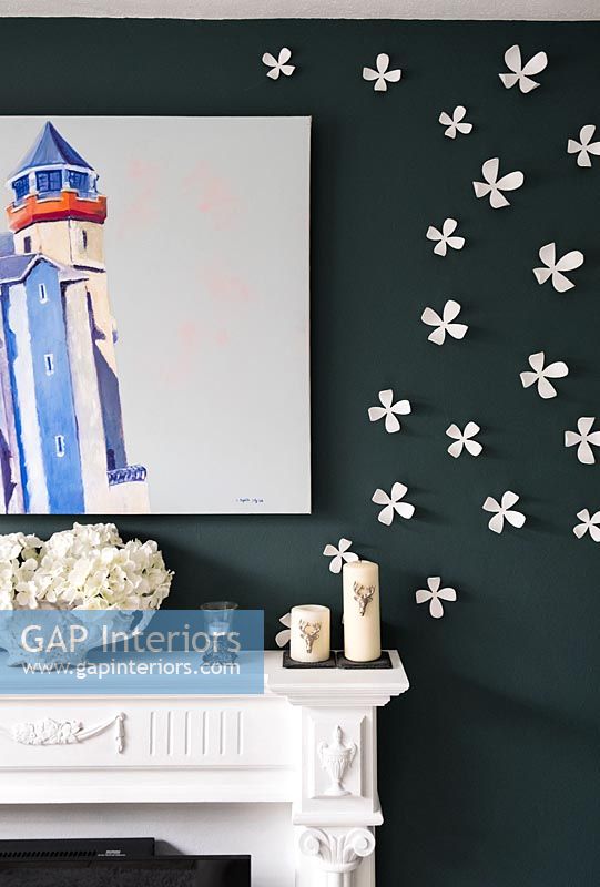 Dark painted wall with raised white flowers and artwork 