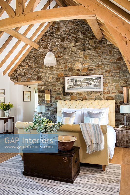 Country bedroom with exposed stone wall and vaulted ceiling 