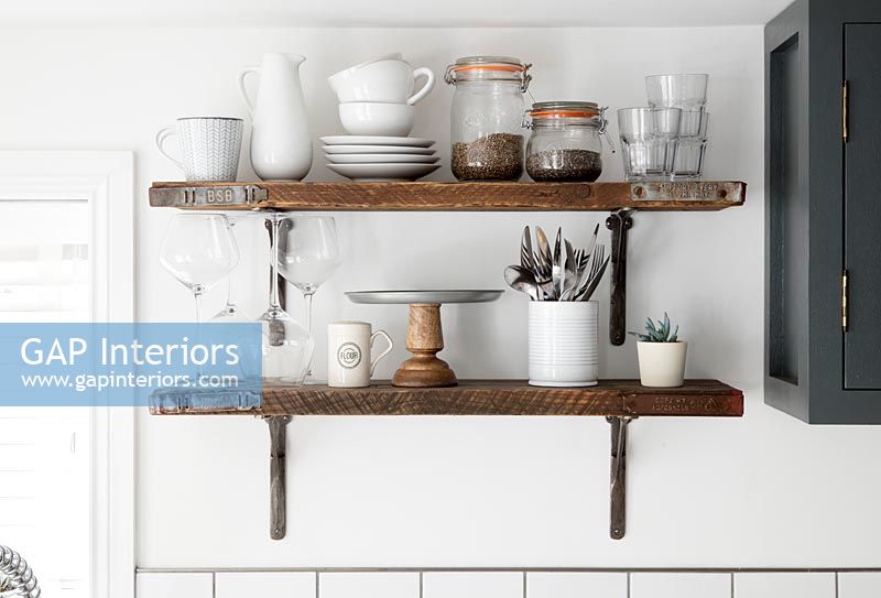 Wooden shelves in kitchen with storage jars and plates 