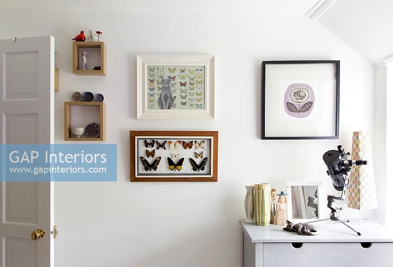 Framed art and butterflies on bedroom wall 