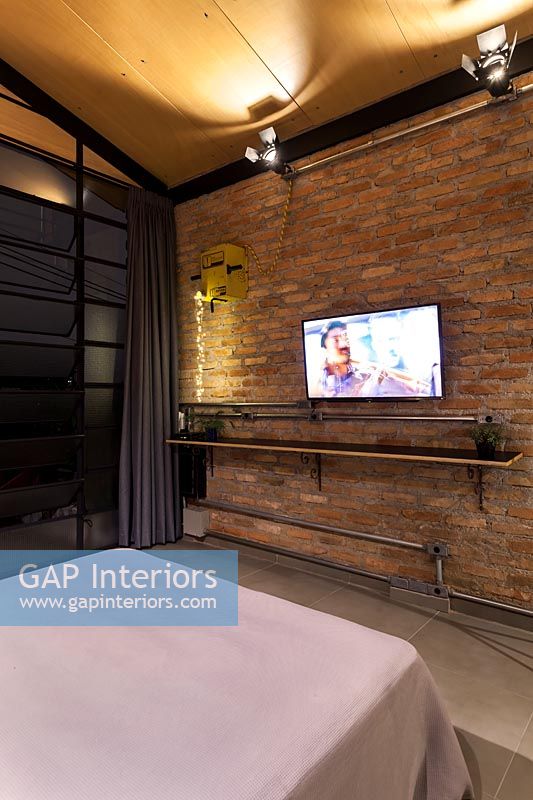 Modern industrial bedroom with wall mounted television 
