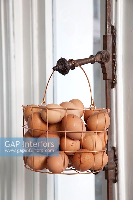 Metal basket of eggs hanging on metal handle 