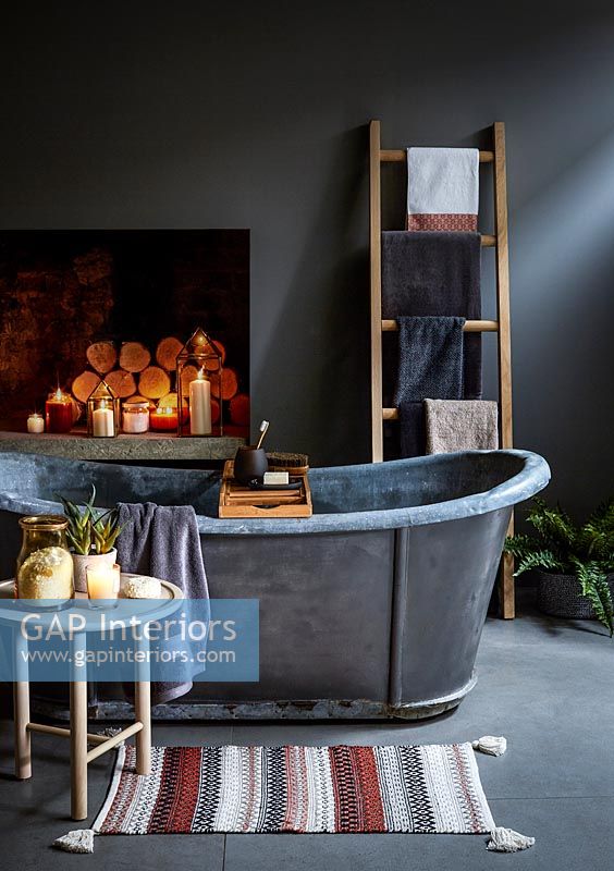 Freestanding metal bath in dark grey bathroom with concrete floor 