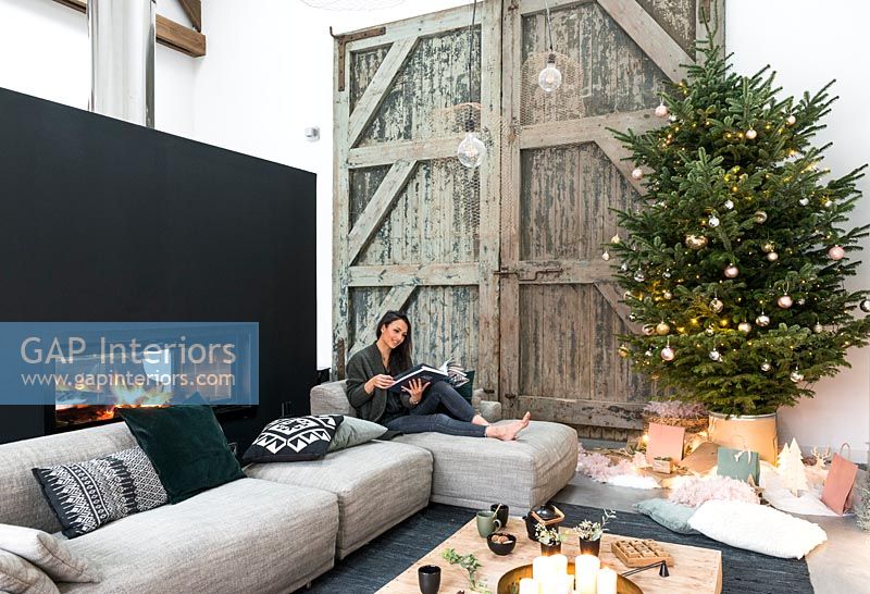 Woman reading in modern country living room decorated for Christmas 
