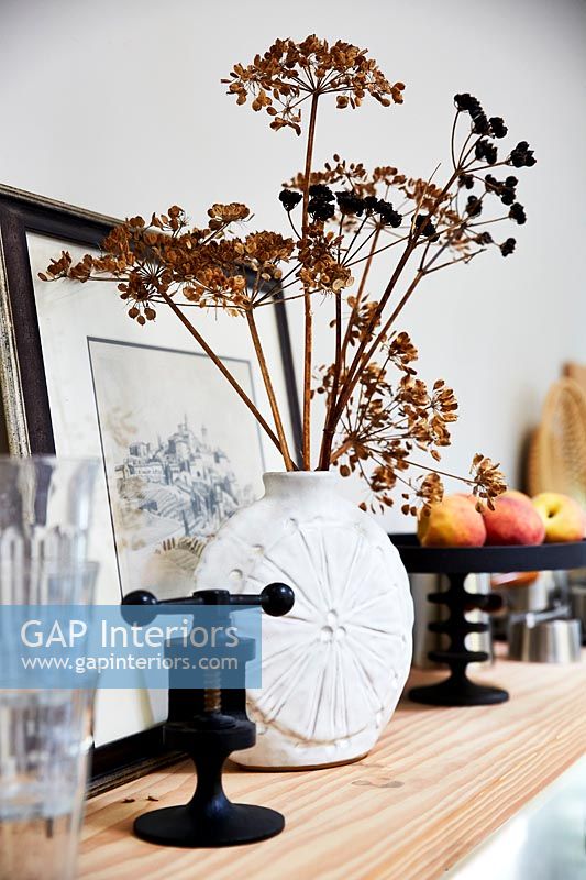Dried flowers and seed heads in vase on shelf 