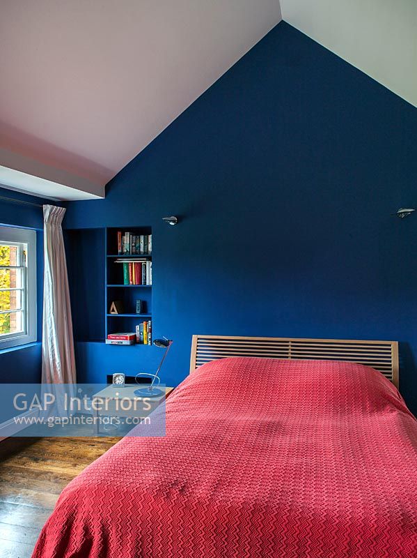 Bedroom with red bedspread and blue painted walls 