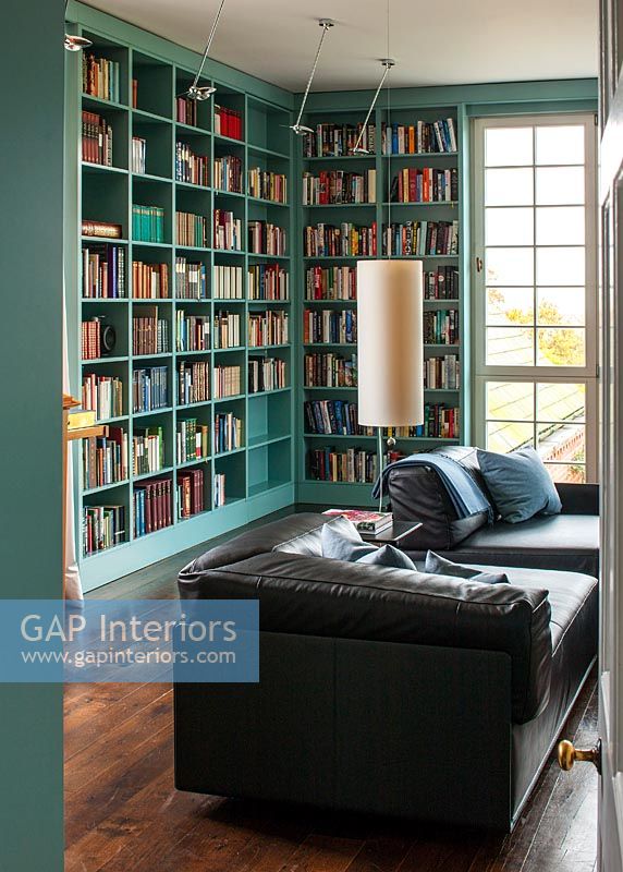Black leather sofa in library with turquoise painted bookshelves 