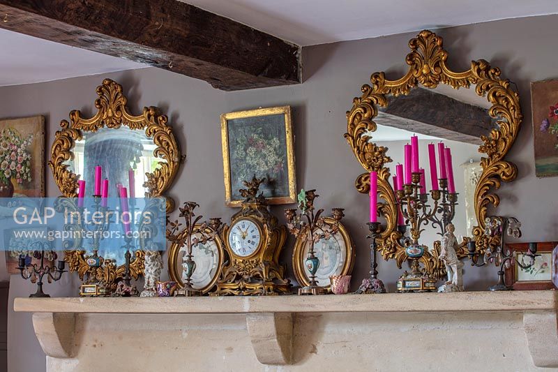 Candles, clocks and vintage mirrors on mantelpiece 