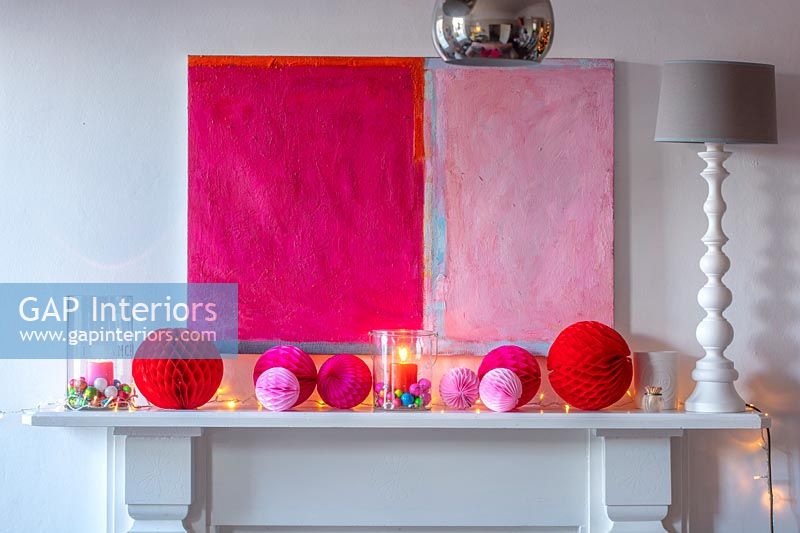 Pink modern artwork and Christmas decorations over fireplace 