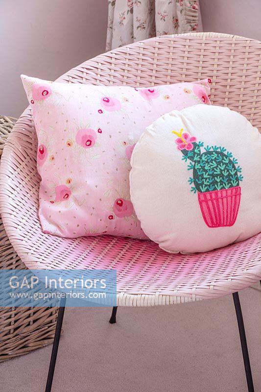 Modern patterned cushions on pink rattan chair 