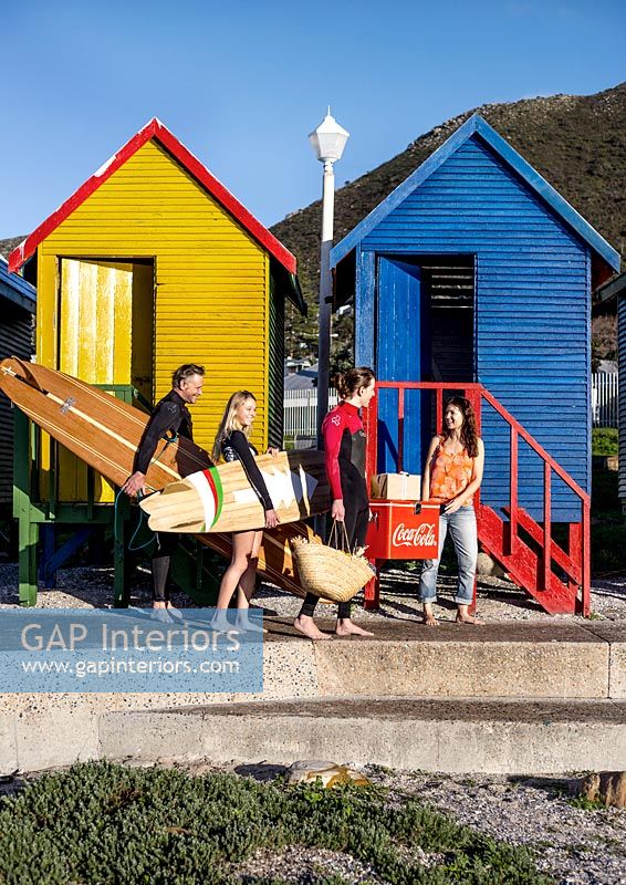 Surfers next to colourful beach huts 